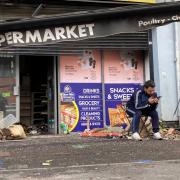 Abdelkader Mohamad Al Alloush sits outside his Belfast shop, which was torched in far-right riots on Saturday