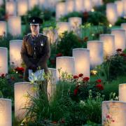 A soldier amongst military graves illuminated during part of a military-led vigil to commemorate the 100th anniversary of the beginning of the Battle of the Somme