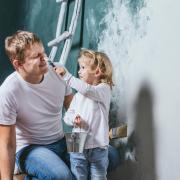 Family, happy daughter with dad doing home repair, paint walls, together with love.