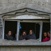 Palestinians look at the destruction after an Israeli air strike on a crowded tent camp housing Palestinians displaced by the war