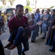 A Palestinian man carries an injured child after an Israeli airstrike in Deir al Balah, Gaza