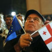 A demonstrator holds an EU and a Georgian national flags attending an opposition protest against the results of the parliamentary election in Tbilisi, Georgia