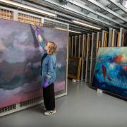 Exhibition curator, Kirsty Matheson, dusting Jon Schueler's Storm at Sea Remembered ahead of it being installed