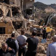 People watch as emergency response workers look for bodies in the rubble of a building that was hit by a Israeli airstrike