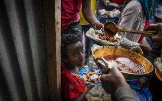 Elena, 7, centre, lines up with other displaced to receive food donated by local residents at a reception centre for the internally displaced