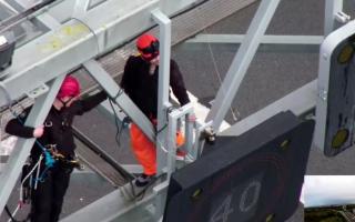 A specialist police officer, trained to work at heights working to remove a protester from the gantry over junction 30 of the M25