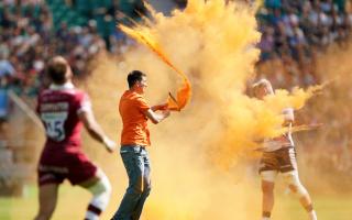 A Just Stop Oil protester throws orange paint powder over a player during the Gallagher Premiership final