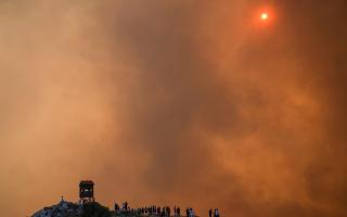People watch a wildfire in Mandra, west of Athens, in 2023