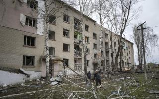 Local men cut a tree in front of a residential building which was heavily damaged by a Russian airstrike in Lukiantsi in the Kharkiv region