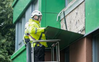 Workers remove potentially dangerous cladding from a tower block