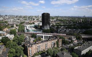 A tube train passes the remains of Grenfell Tower