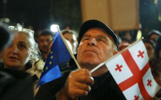 A demonstrator holds an EU and a Georgian national flags attending an opposition protest against the results of the parliamentary election in Tbilisi, Georgia