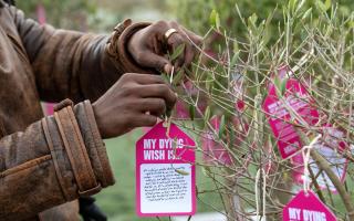 A person attaches a dying wish to a tree during an event in support of assisted dying law outside the Scottish Parliament in Edinburgh