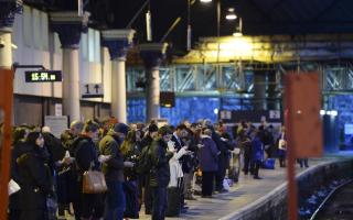 Commuters on a platform at Glasgow Queen Street Station wait for their trains